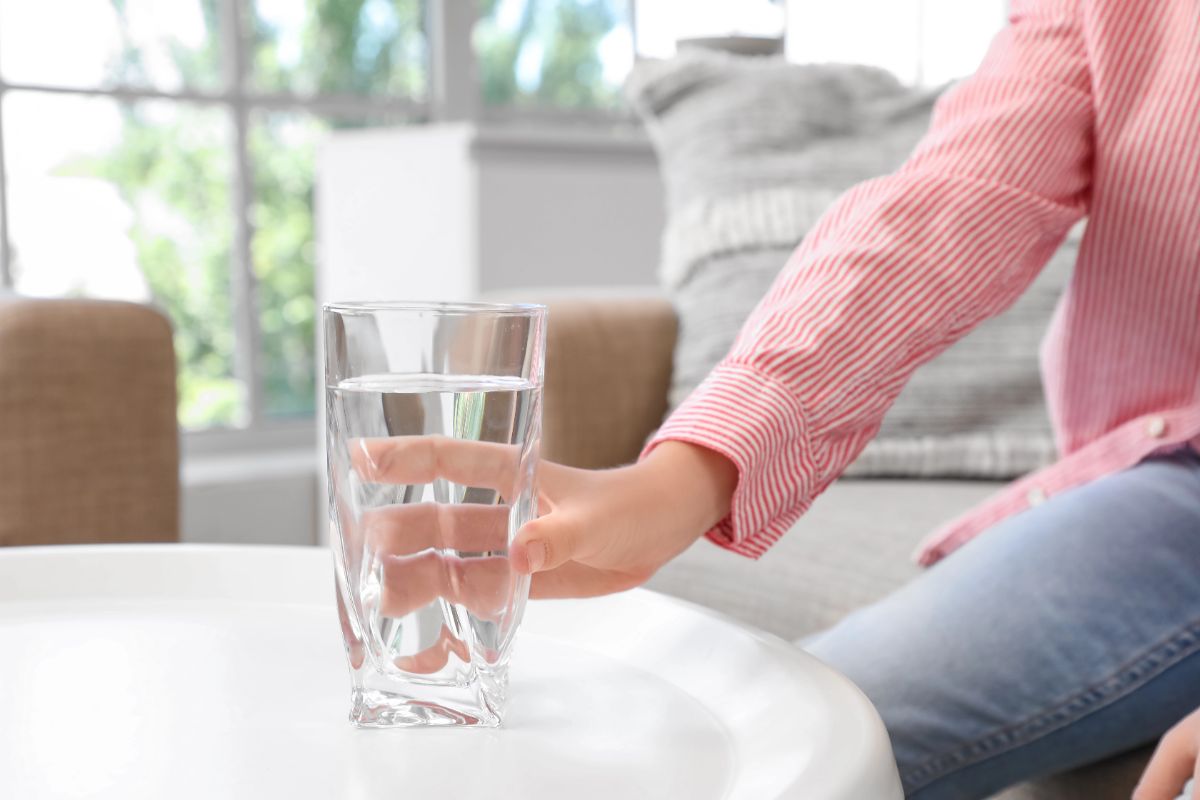 Person reaching for a glass of drinking water at home